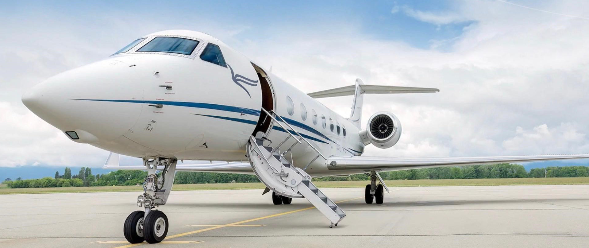 Aereo jet privato bianco parcheggiato sulla pista con scaletta aperta e cielo nuvoloso
